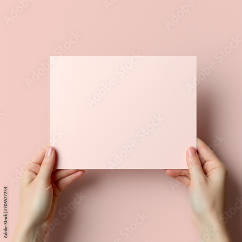 fotografia de estilo mockup con detalle de hoja de papel de tonos rosados, sostenida por unas manos, sobre fondo neutro photo