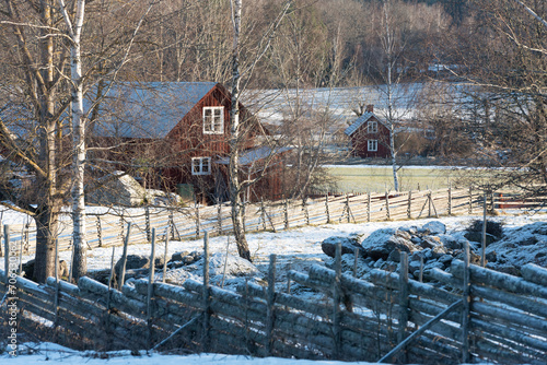 Swedish landscape in winter with traditional fences and red wooden house