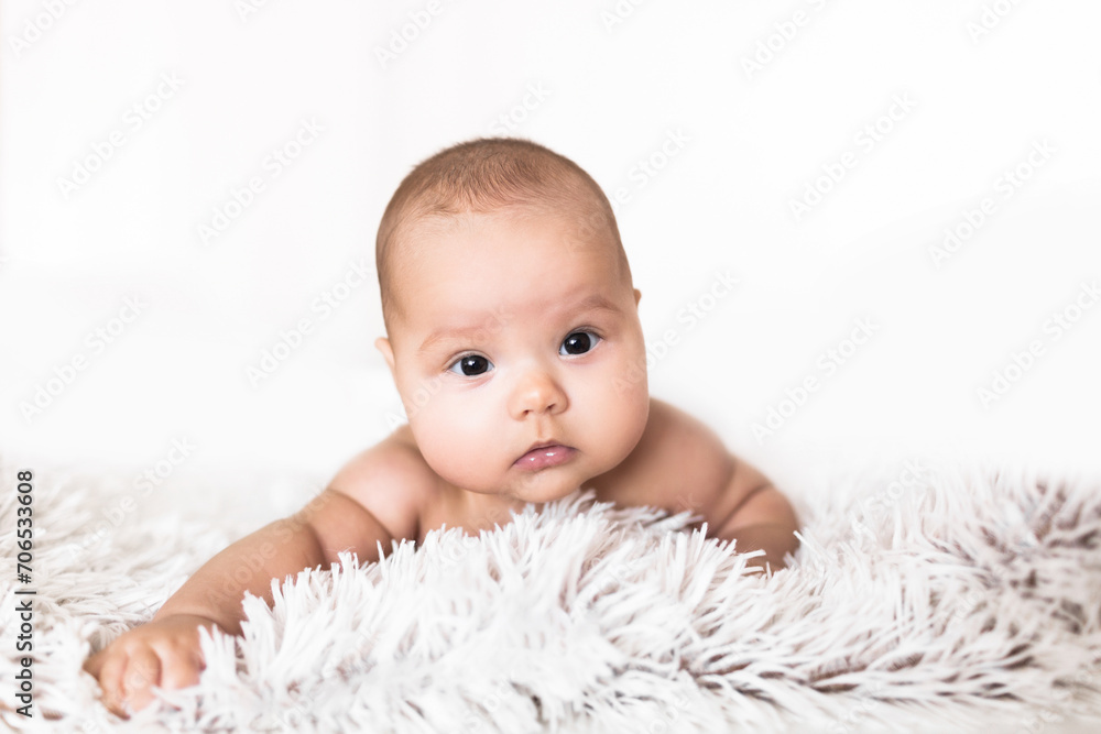 Portrait of an infant on a white background. Portrait of a baby lying on his belly against a white background Portrait of an infant on a white background. Portrait of a baby lying on his belly against a white background