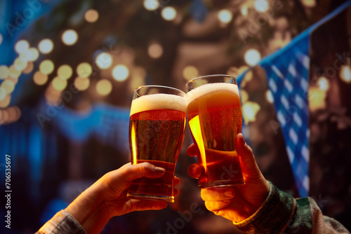 Close up image of hands holding glasses of beer and clinking after toast. Old friends sitting in bar and celebrating beginning of football season. Concept of Oktoberfest, party, taste, traditions. photo