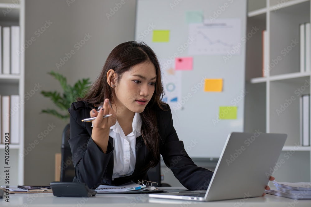Portrait of young Asian woman working on laptop in modern office Perform accounting analysis, report investment data. Financial concepts and tax system Portrait of young Asian woman working on laptop in modern office Perform accounting analysis, report investment data. Financial concepts and tax system