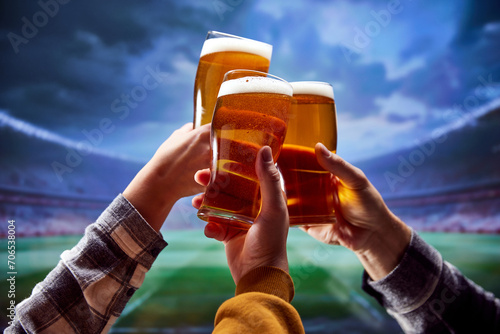 Three hands clinking with glasses of cold light beer. Football fans sitting at tribunes watching match and drinking alcohol drinks. Concept of traditions, taste, festival, friendship. photo