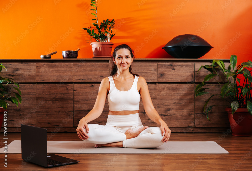 Beautiful woman in lotus position doing yoga online.