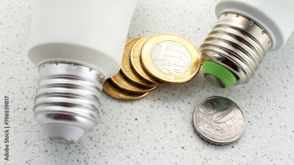 Bright light bulb on Brazilian coins, illustrating the concept of economy and its implications on the electricity bill. Bright light bulb on Brazilian coins, illustrating the concept of economy and its implications on the electricity bill.
