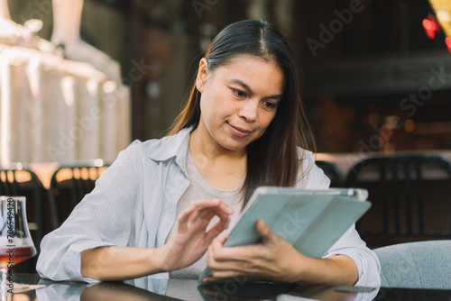 Portrait of beautiful asian woman with smartphone, relaxing in cafe, sitting and enjoying coffee while using tablet remote work business schedule planner.