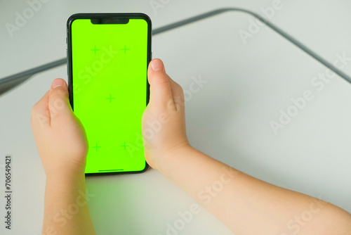 Close-up of children's hands holding smartphone with green screen