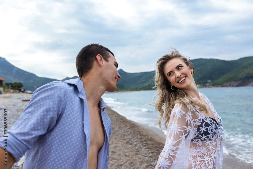 Happy young couple laughing and holding hands on the beach