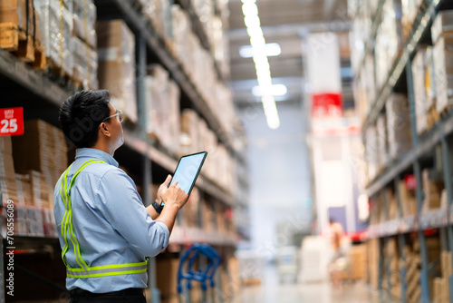 Warehouse worker in security uniform with tablet computer looking at merchandise in large warehouse Logistics and export business Logistics distribution center.
