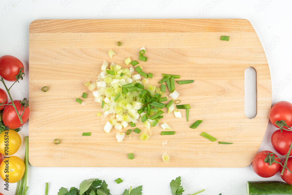 Top view of finely chopped green onions on a wooden cutting board. Top view of finely chopped green onions on a wooden cutting board.