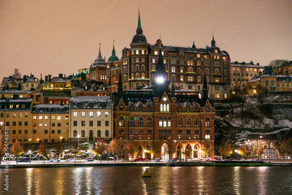 Stockholm, district of Sodermalm at night in winter with snow on the ground, historic buildings. Cloudy sky, lake reflections.