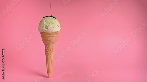 creative concept with unstable pistachio ice cream cone with chocolate sauce  on pink background photo