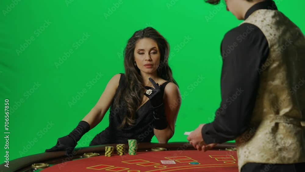 Portrait of female on chroma key green screen. Woman sitting at blackjack poker table playing with male croupier takes cards and placing bet. Portrait of female on chroma key green screen. Woman sitting at blackjack poker table playing with male croupier takes cards and placing bet.
