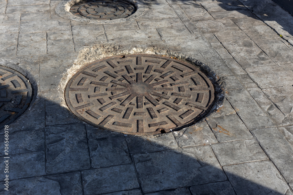 Manhole on the street next to a sidewalk, rusty manhole cap, grunge manhole cover, round edge, Rusty manhole cap, grunge manhole cover