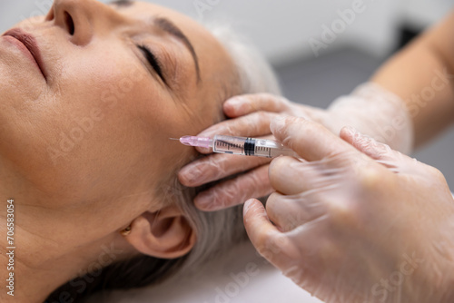 Beautician doing filler injections to a mature female patient