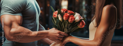 a muscular man gives flowers to a woman. A romantic gift for a girl. photo