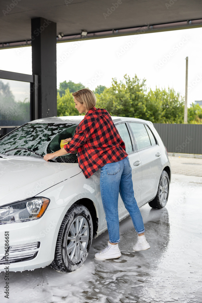 Blonde woman washing the windscreen of the car Blonde woman washing the windscreen of the car