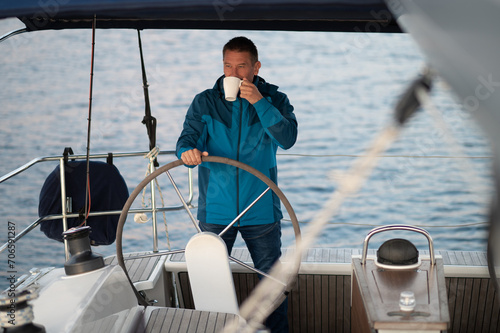 Good-looking mature man sailing a yacht and looking confident