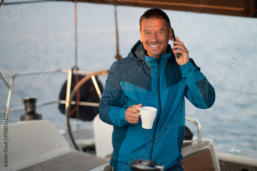 Man on the yacht with a cup of coffee talking on the phone
