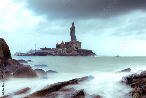 lighthouse on the coast of the sea at kanyakumari place in India, slow shutter milky water at Thiruvalluvar Statue in a cloudy day photo