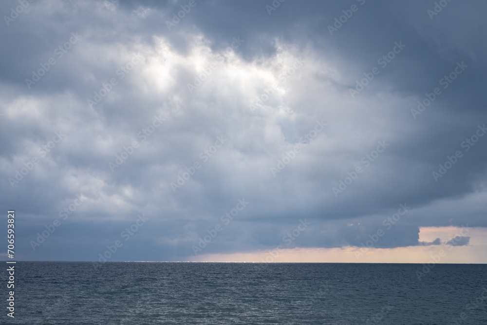 Dark dramatic view of clouds and stormy weather over the Black Sea, the sun's rays pass through dense thunderclouds in the middle of a gloomy sea Dark dramatic view of clouds and stormy weather over the Black Sea, the sun's rays pass through dense thunderclouds in the middle of a gloomy sea