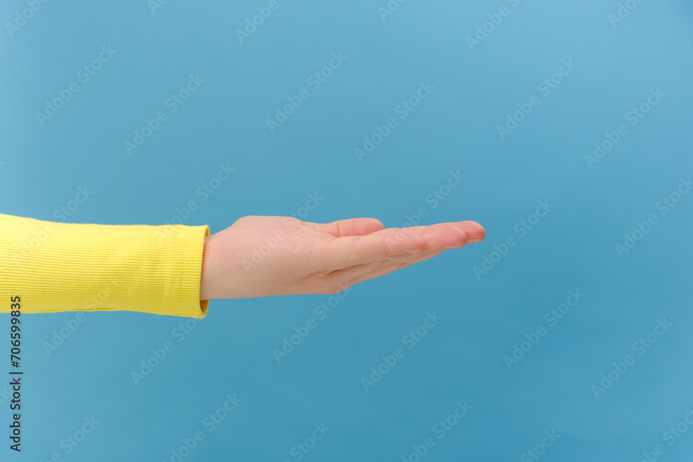 Close up of female hand outstretching hand, giving or taking something, presenting copy space for promotion content on palm, posing isolated over plain blue color background wall in studio Close up of female hand outstretching hand, giving or taking something, presenting copy space for promotion content on palm, posing isolated over plain blue color background wall in studio