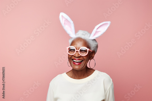 African American senior old woman with cute bunny rabbit ears on studio pink orange background. Empty space place faor text, copy paste, horizontal banner photo