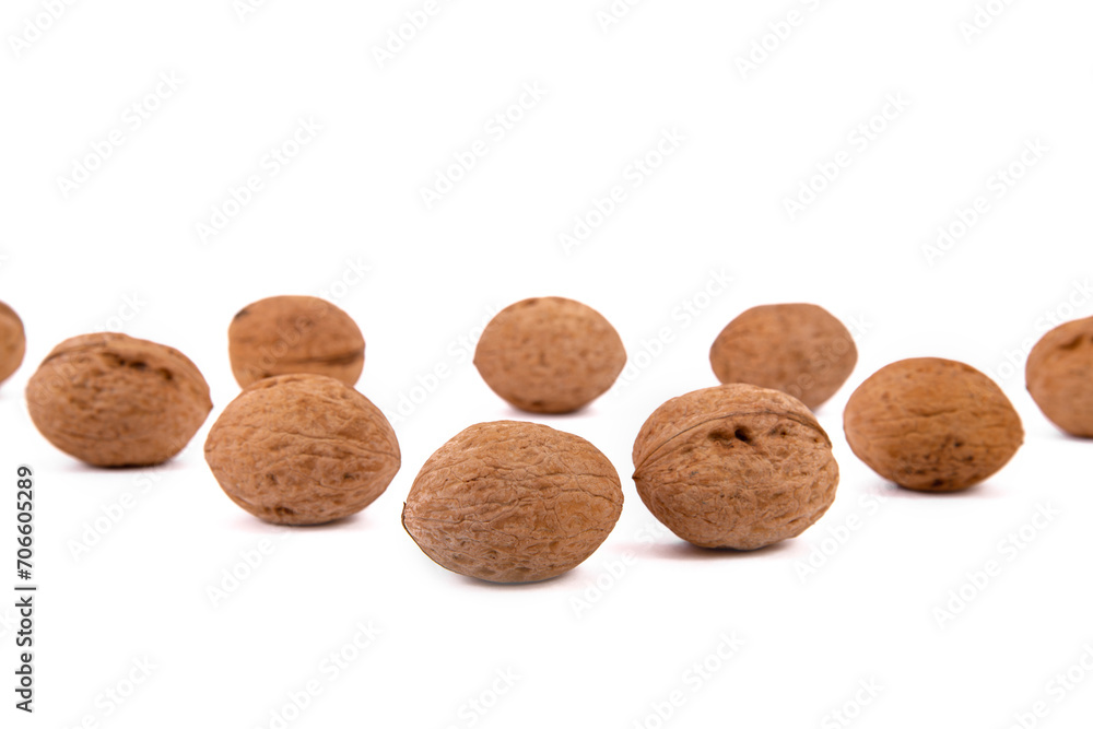 Scattered whole walnuts lie on a white background. Backgrounds and textures. Isolate.