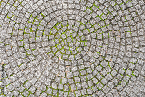 Patio pavers circle design overhead view.
Cut square stones in weathered floor with green moss. photo
