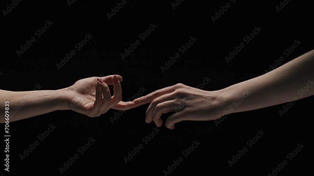 Portrait of female model isolated on black background in studio. Two women naked hands stretching to each other touch fingers. Portrait of female model isolated on black background in studio. Two women naked hands stretching to each other touch fingers.