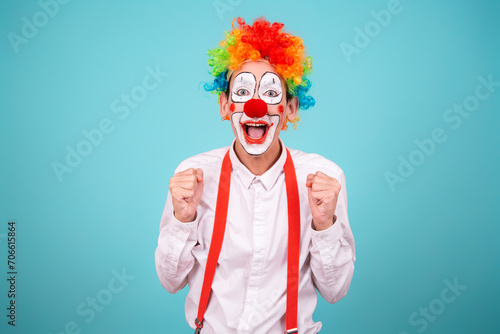A joyful clown. A cute man in a suit and makeup for a holiday for children. A fool. Blue background. Copy the space.