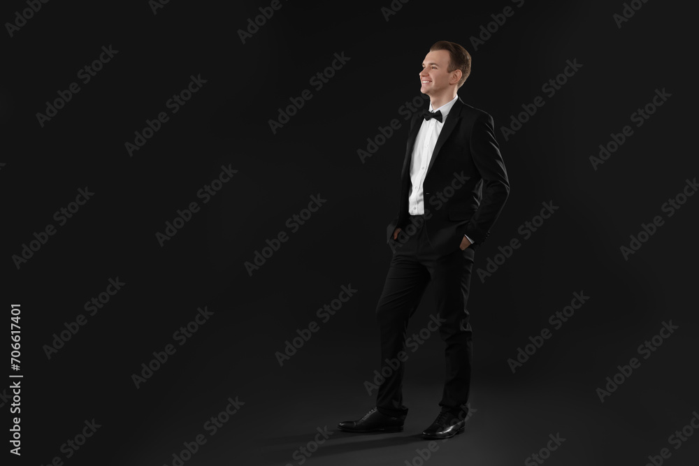 Handsome young man in stylish suit on black background, space for text Handsome young man in stylish suit on black background, space for text