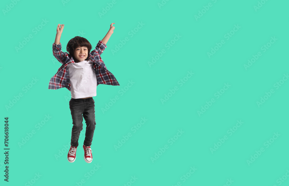 Happy boy jumping on turquoise background, space for text Happy boy jumping on turquoise background, space for text