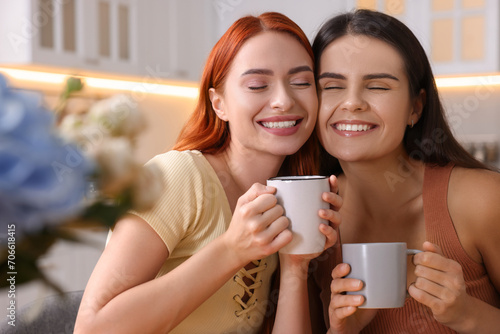 Portrait of happy young friends with cups of drink at home