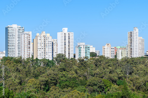 Tall buildings behind a vast green area of trees. Green city concept. Photo taken in Sao Paulo - SP, Brazil. © Vinícius Bacarin