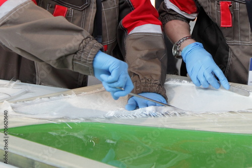 Industrial plant employees cut and put fiberglass into a matrix for infusion with epoxy resin in the production of fiberglass products