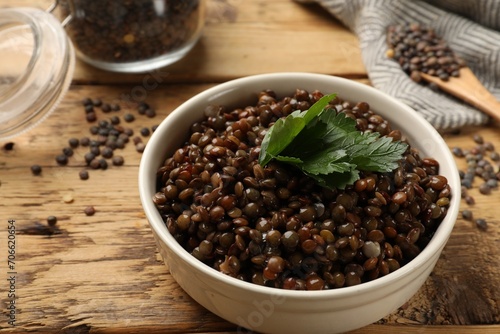 Delicious lentils with parsley in bowl on wooden table  closeup. Space for text