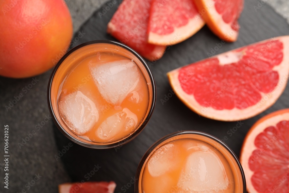 Tasty grapefruit drink with ice in glasses and fresh fruits on dark table, flat lay Tasty grapefruit drink with ice in glasses and fresh fruits on dark table, flat lay