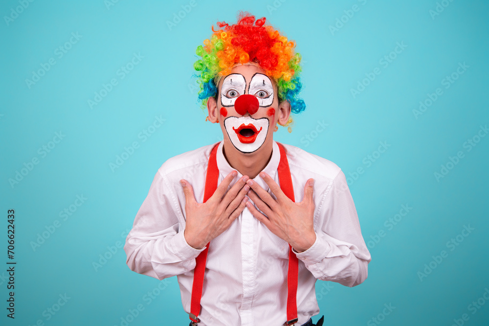 A joyful clown. A cute man in a suit and makeup for a holiday for children. A fool. Blue background. Copy the space. A joyful clown. A cute man in a suit and makeup for a holiday for children. A fool. Blue background. Copy the space.