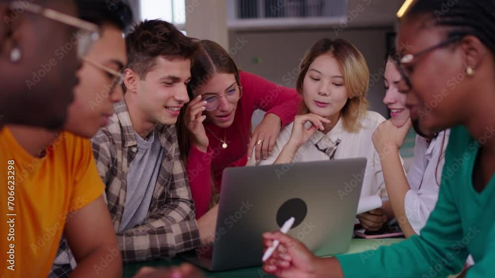 Selective focus on a smiling male young university student using laptop in the cafeteria on campus with his female classmates. Academic multiracial people studying together on the faculty building Selective focus on a smiling male young university student using laptop in the cafeteria on campus with his female classmates. Academic multiracial people studying together on the faculty building