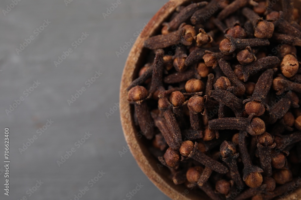 Fototapeta premium Aromatic cloves in bowl on grey table, top view. Space for text