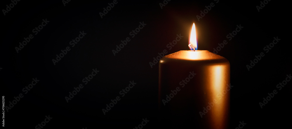 Fototapeta premium Candle burning in darkness over black background