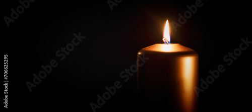 Candle burning in darkness over black background