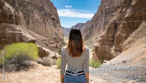 a young woman alone in nature seen from behind in front of a canyon ready to cross the desert a journey through the difficulties and trials of life towards the unknown adventure and freedom photo