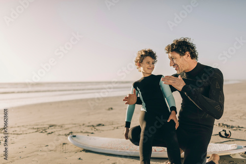 Father giving surfing tips to son at the beach photo