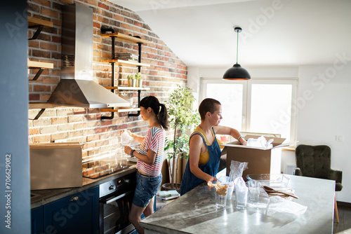 Lesbian couple unpacking boxes and setting up their new kitchen photo