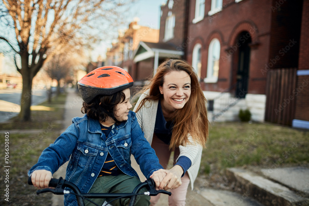 Fototapeta premium Mother teaching child to ride a bicycle in suburb
