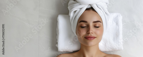 Happy beautiful young woman with white towel turban on head relaxing and enjoying facial treatment photo