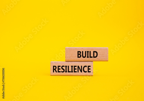 Build resilience symbol. Wooden blocks with words Build resilience. Beautiful yellow background. Business and Build resilience concept. Copy space. photo