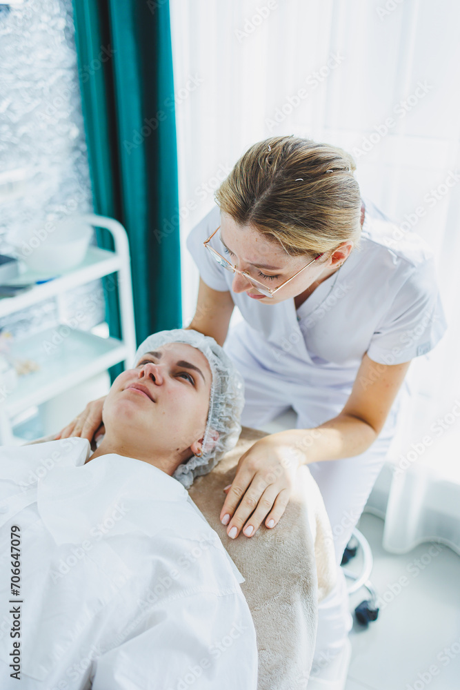 A young woman at an appointment with a beautician. A cosmetologist gives a face massage to her client. Facial. A trip to the beautician. A young woman at an appointment with a beautician. A cosmetologist gives a face massage to her client. Facial. A trip to the beautician.