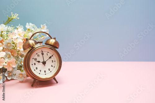 Vintage alarm clock with flowers decorations on pink and blue background